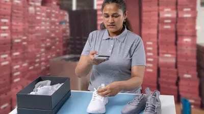 Woman checking shoes with Origify in a warehouse after they have been returned